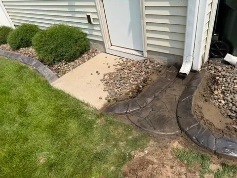 Landscaped area with deck and concrete path in Princeton, MN